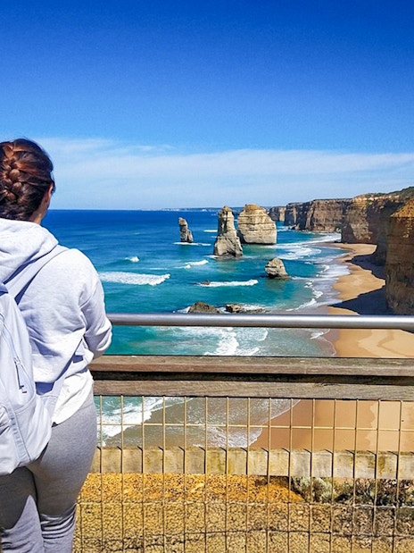 Woman at viewpoint overlooking 12 Apostles on Great Ocean Road, Australia.