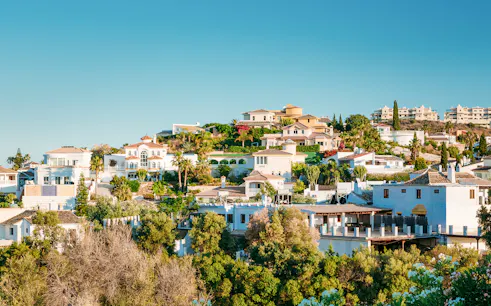 Hillside view of whitewashed houses in Mijas, Spain, surrounded by greenery.