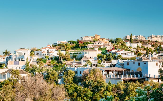 Hillside view of whitewashed houses in Mijas, Spain, surrounded by greenery.