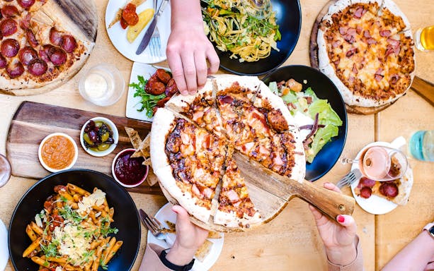 Frankie's on Rotto lunch spread with pizza, pasta, and salads on a wooden table.