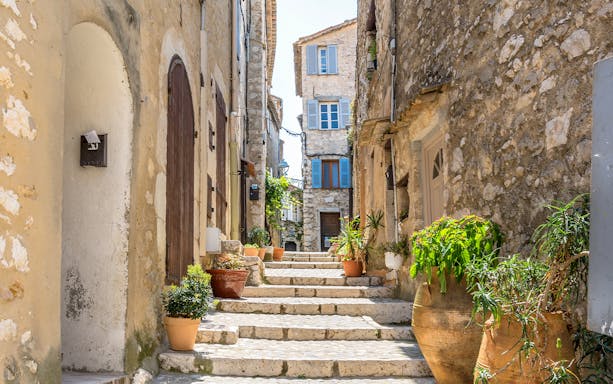 Stone alley with potted plants in Saint Paul de Vence, France.