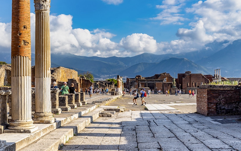 Pompeii Forum view from via del Foro with ancient columns and distant mountains.