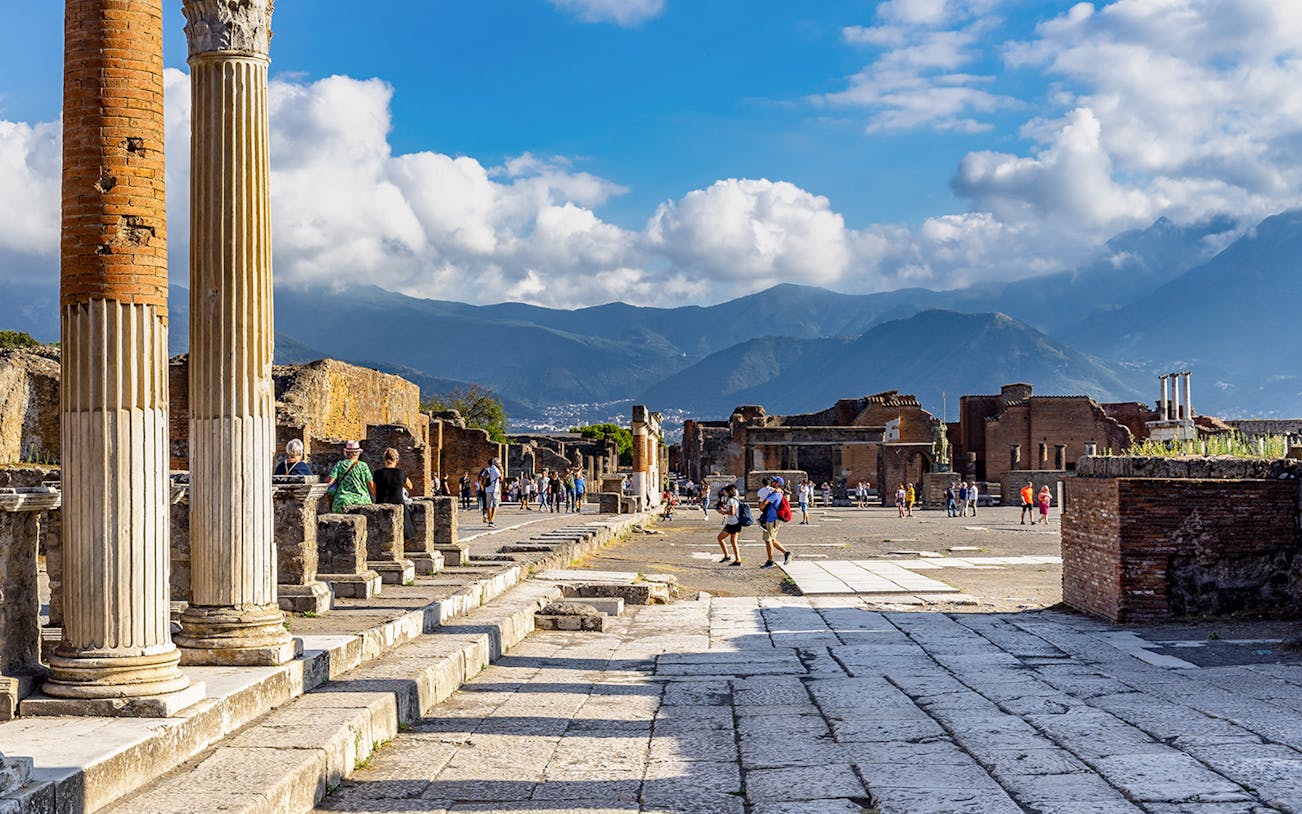 Pompeii Forum view from via del Foro with ancient columns and distant mountains.