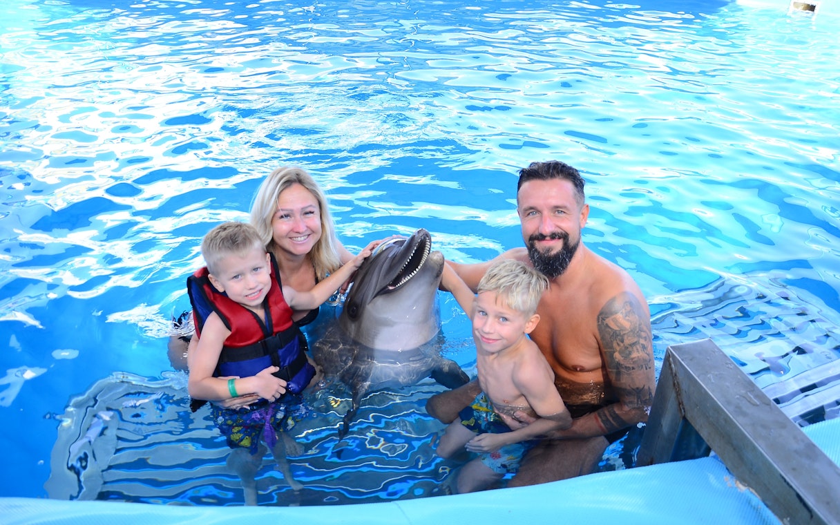 Family posing with dolphin at Egypt Dolphin World, Hurghada.