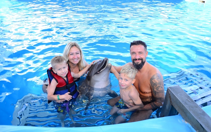 Family posing with dolphin at Egypt Dolphin World, Hurghada.