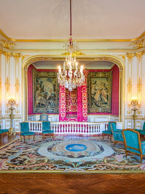 Chambord Castle king's room with ornate decor, tapestries, and chandelier.