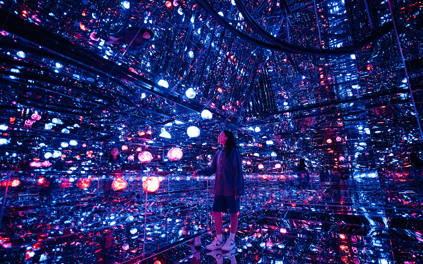 Tourist exploring mirrored room with colorful lights at House of Hype, Dubai.