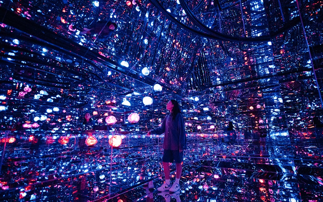 Tourist exploring mirrored room with colorful lights at House of Hype, Dubai.