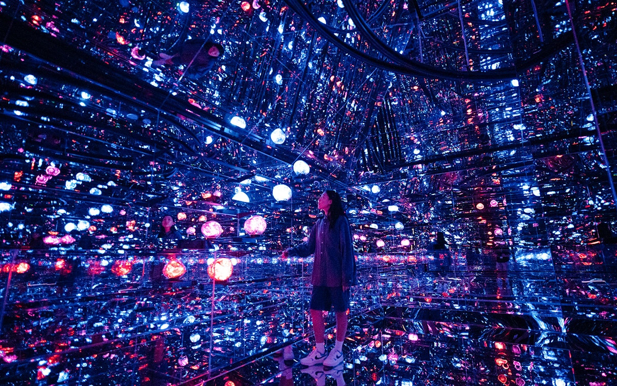 Tourist exploring mirrored room with colorful lights at House of Hype, Dubai.