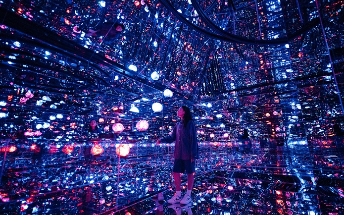 Tourist exploring mirrored room with colorful lights at House of Hype, Dubai.