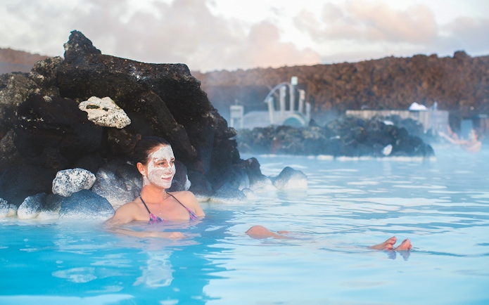 Person relaxing in Blue Lagoon geothermal spa, Iceland, with facial mask.