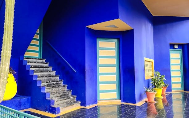 Jardin Majorelle interior with blue walls, stairs, and potted plants in Marrakech, Morocco.