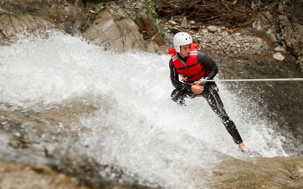 Canyoning adventure in Braga with person rappelling down waterfall.