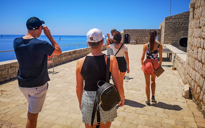 Guests walking along the stone pathway of Lovrijenac Fort, overlooking the sea.