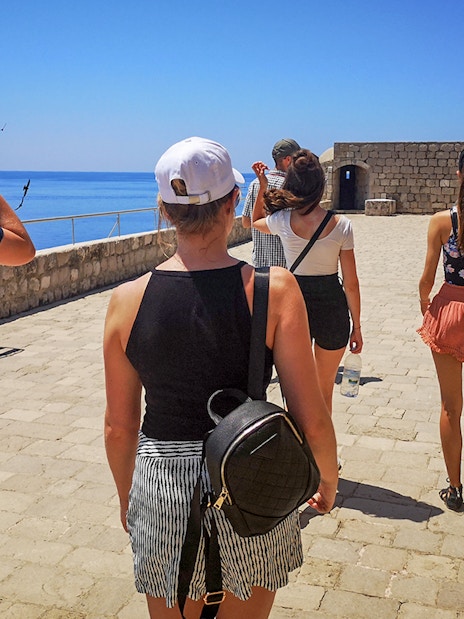 Guests walking along the stone pathway of Lovrijenac Fort, overlooking the sea.