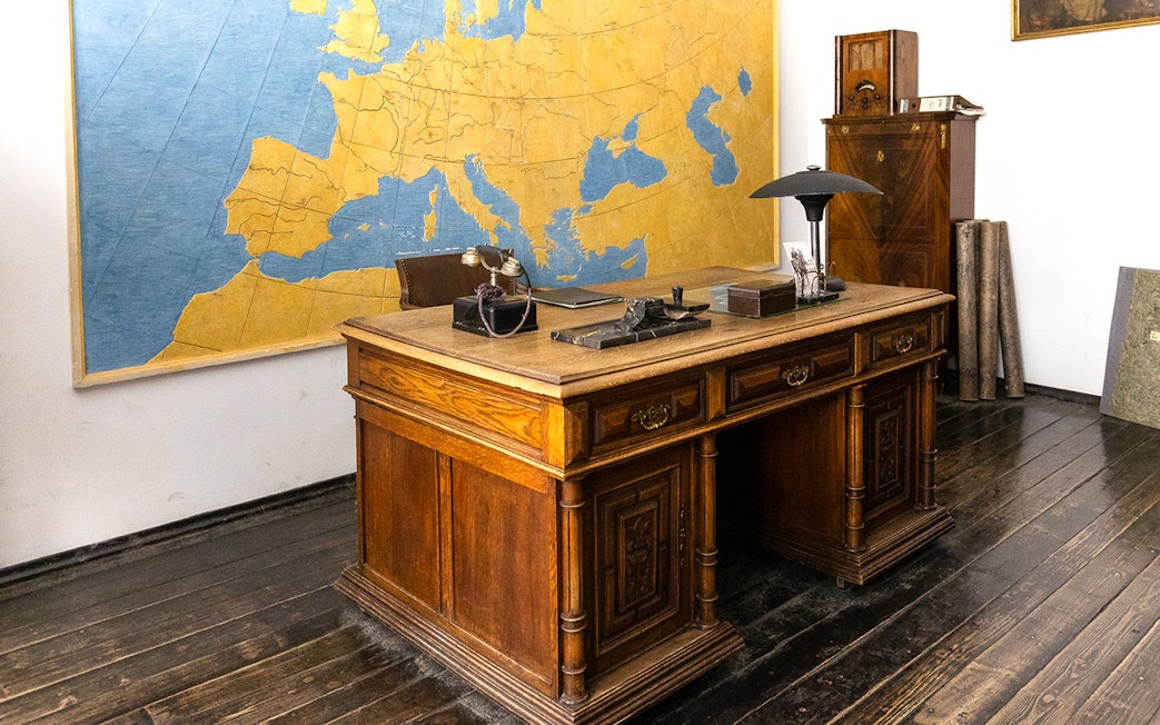 Oskar Schindler's vintage desk and chair in Schindler's Factory, Krakow, with a large map on the wall.