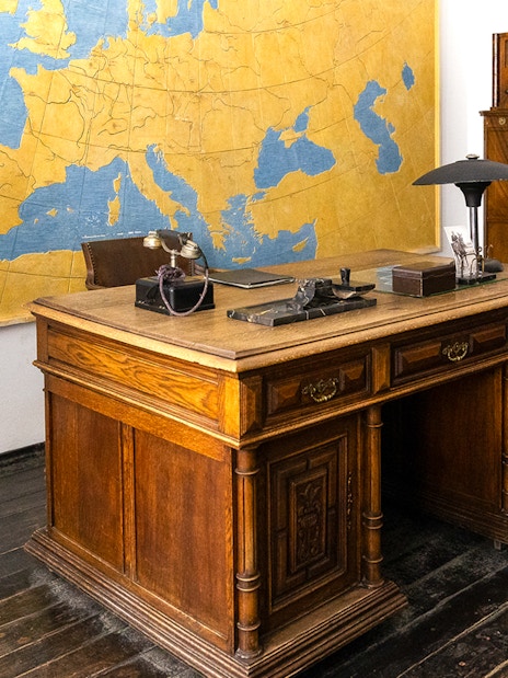 Oskar Schindler's vintage desk and chair in Schindler's Factory, Krakow, with a large map on the wall.