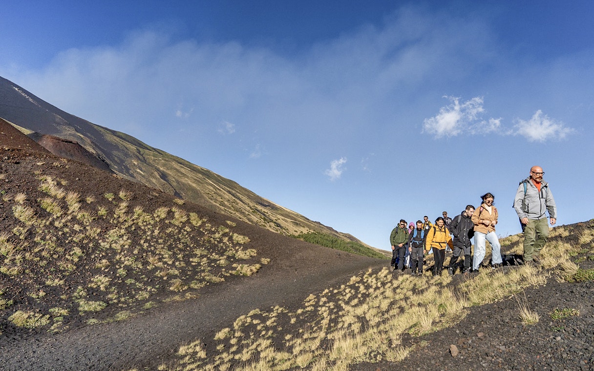 Group hiking on Mount Etna's slopes during Catania morning tour.