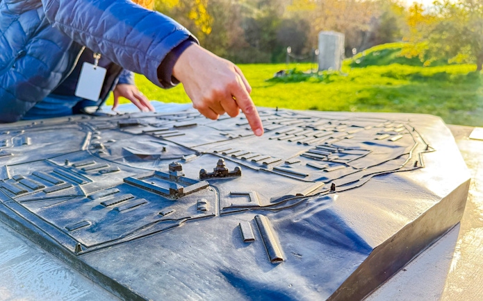 Tour guide pointing at a model of Płaszów Concentration Camp during guided tour.