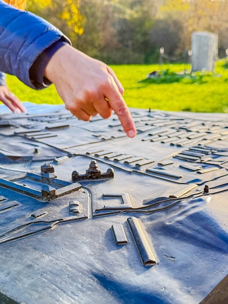 Tour guide pointing at a model of Płaszów Concentration Camp during guided tour.
