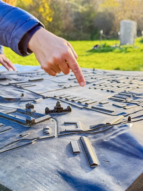 Tour guide pointing at a model of Płaszów Concentration Camp during guided tour.