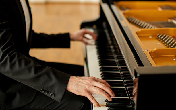 Pianist's hands playing a grand piano keyboard.