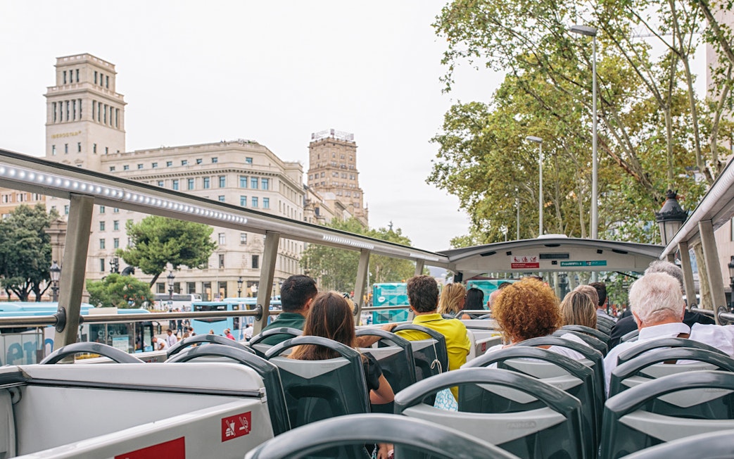Tourists on a Hop on Hop off bus in Barcelona, viewing city landmarks.