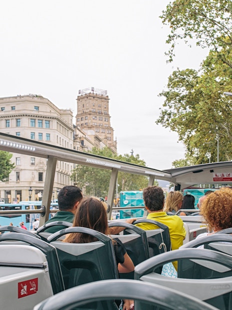 Tourists on a Hop on Hop off bus in Barcelona, viewing city landmarks.