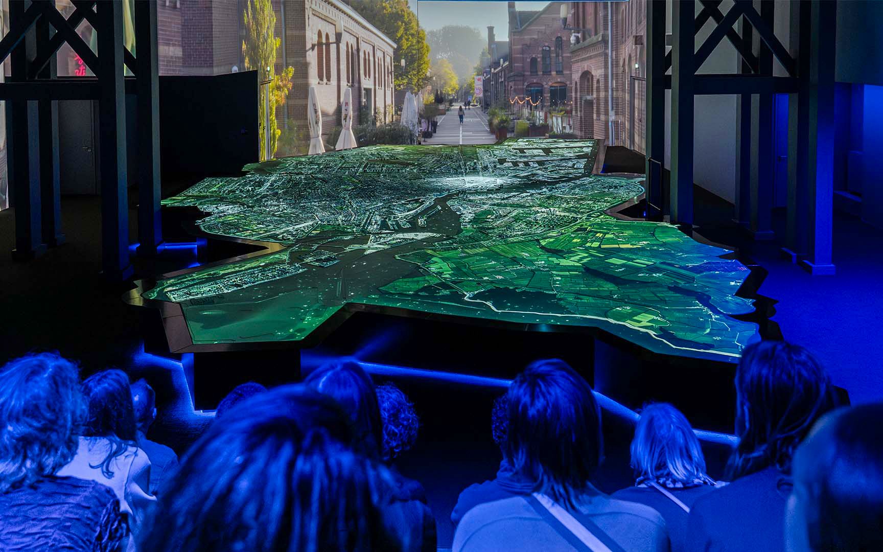 Amsterdam in Motion exhibit with illuminated city map and audience viewing.