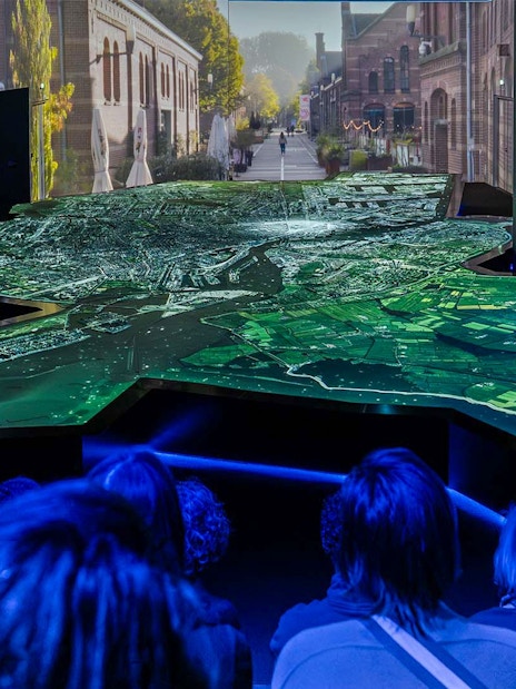 Amsterdam in Motion exhibit with illuminated city map and audience viewing.