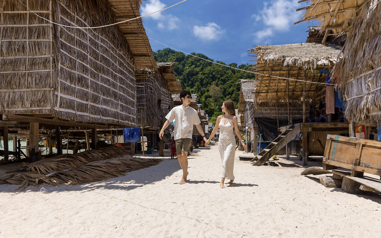 Couple walking through traditional village on Surin Island, Thailand, during a day trip.