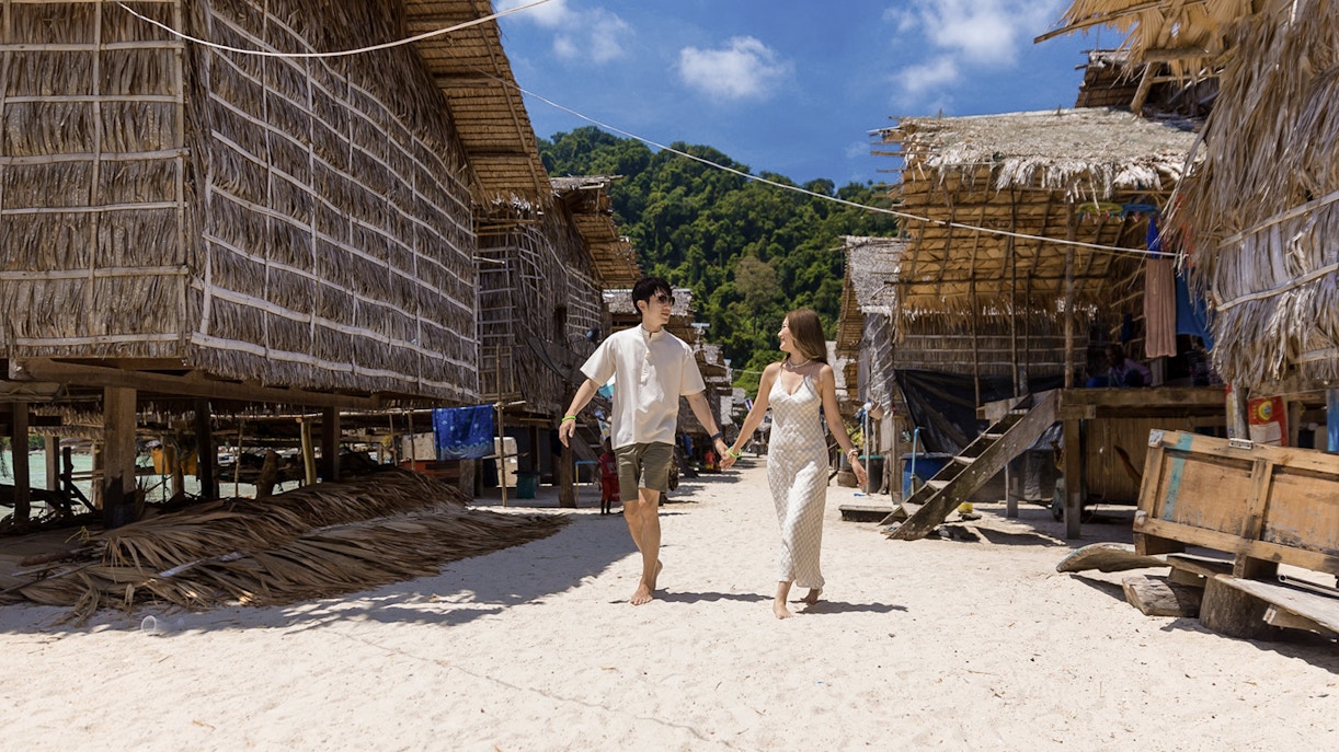 Couple walking through traditional village on Surin Island, Thailand, during a day trip.