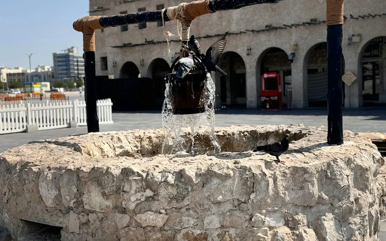 Stone well with pigeons and flowing water in Souq Waqif, Doha.