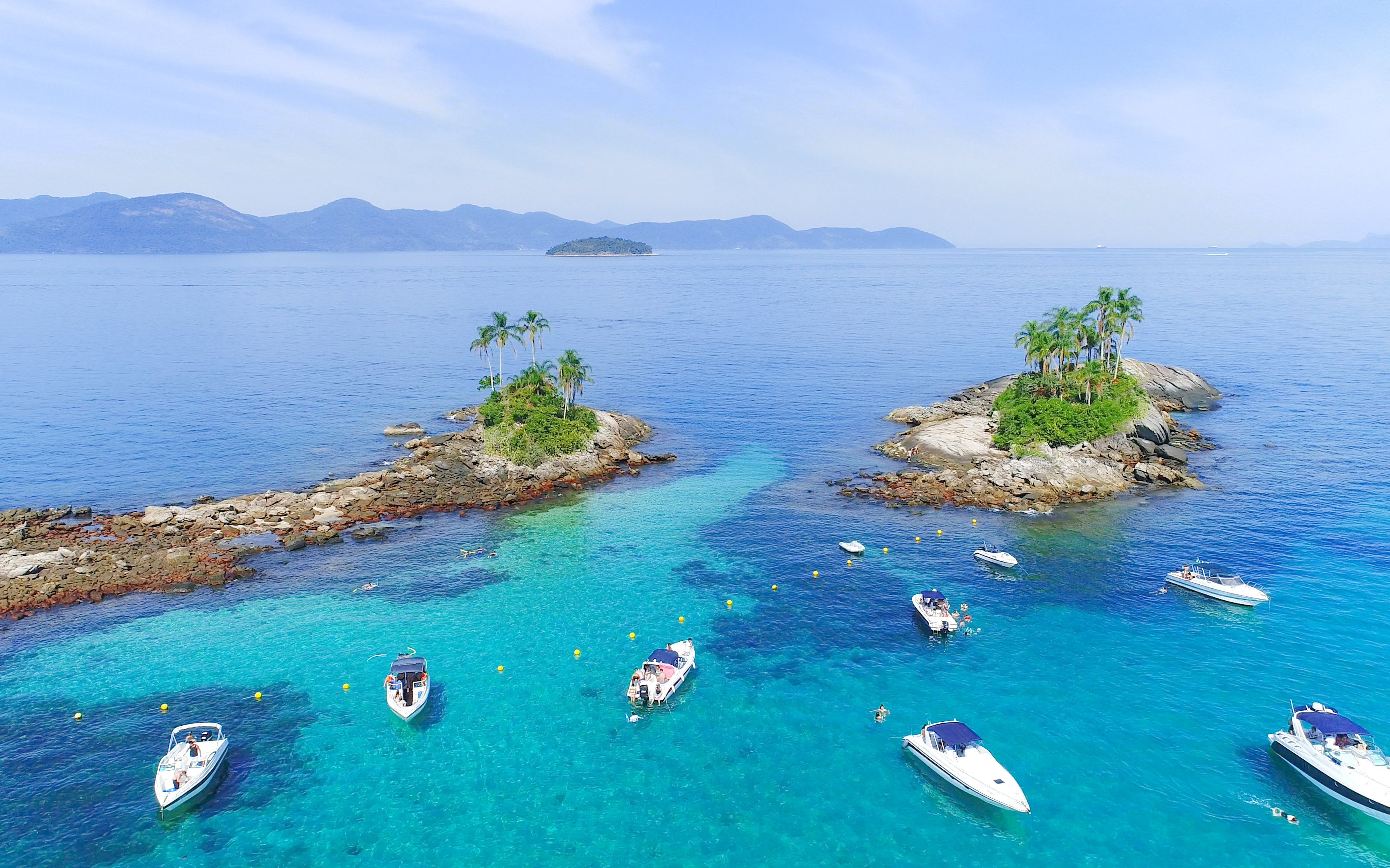 Boats near Ilha Botinas in Angra dos Reis, Rio de Janeiro, with clear blue water and small islands.