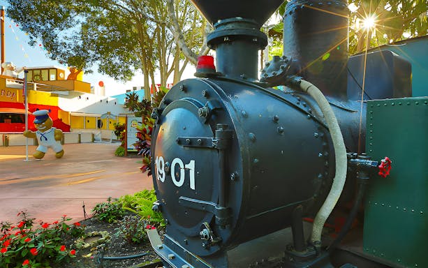 Steam train at The Ginger Factory with a gingerbread man statue in the background.