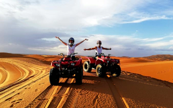 ATVs on Sahara Desert dunes with riders enjoying the view.
