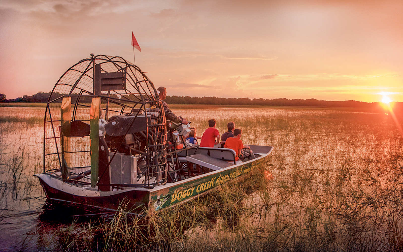 Guests on an airboat tour at sunset in Boggy Creek, Florida.