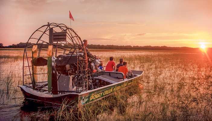 Guests on an airboat tour at sunset in Boggy Creek, Florida.