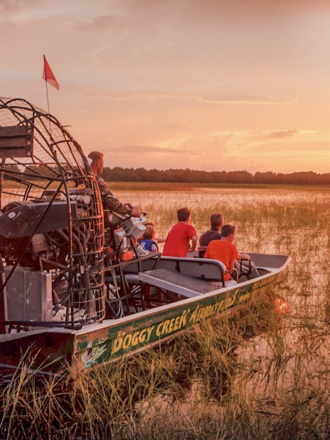 Guests on an airboat tour at sunset in Boggy Creek, Florida.