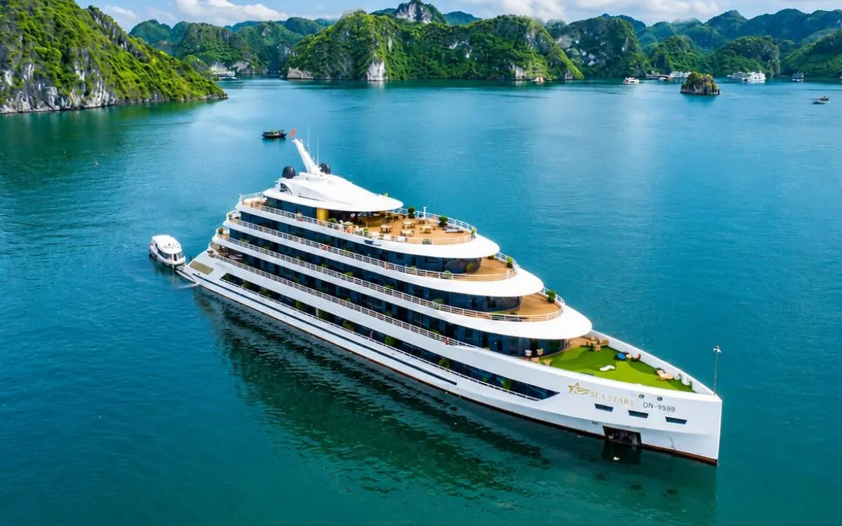 Luxury cruise ship in Ha Long Bay with lush islands in the background.