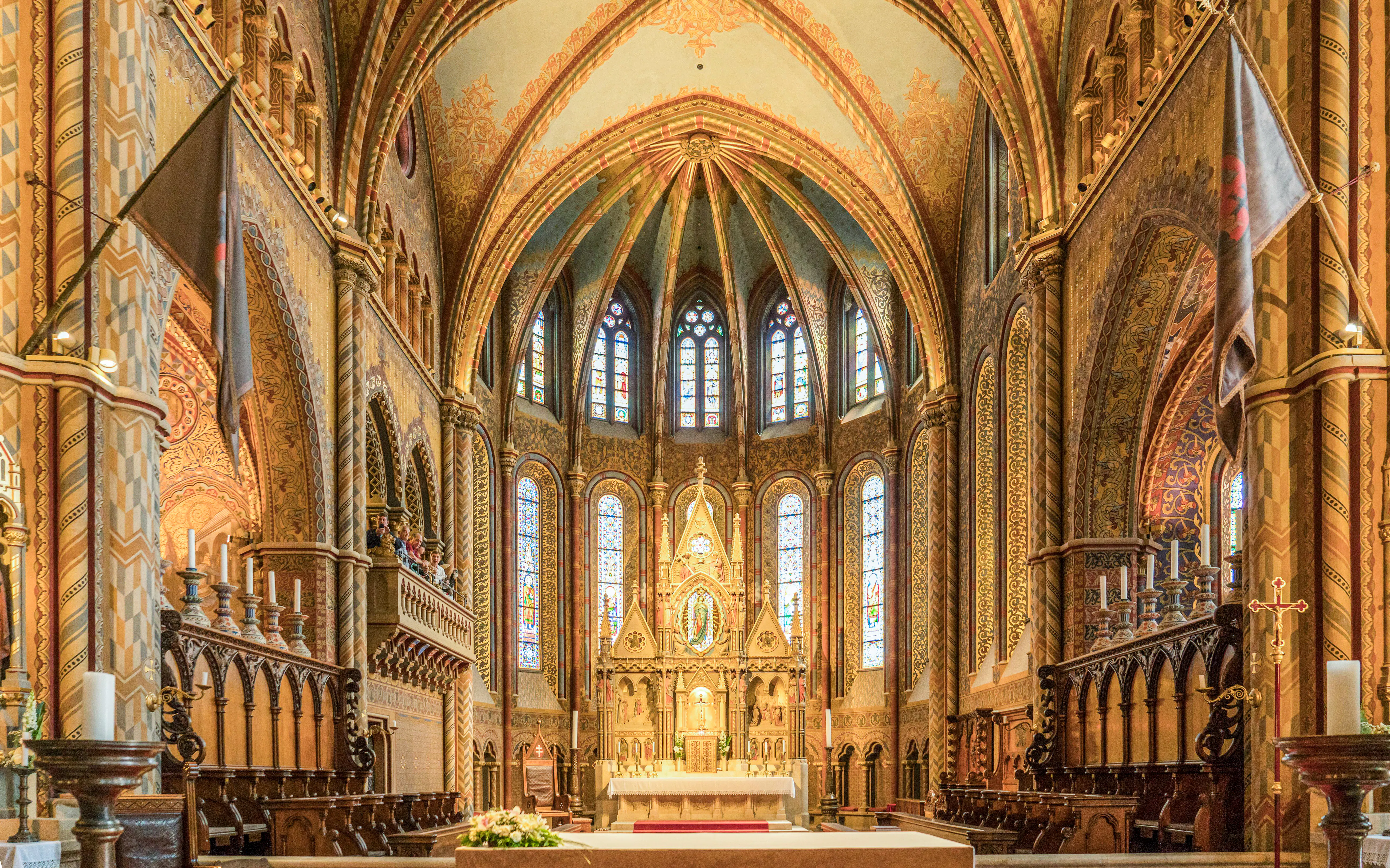 Interior of Matthias Church in Budapest with ornate altar and stained glass windows.