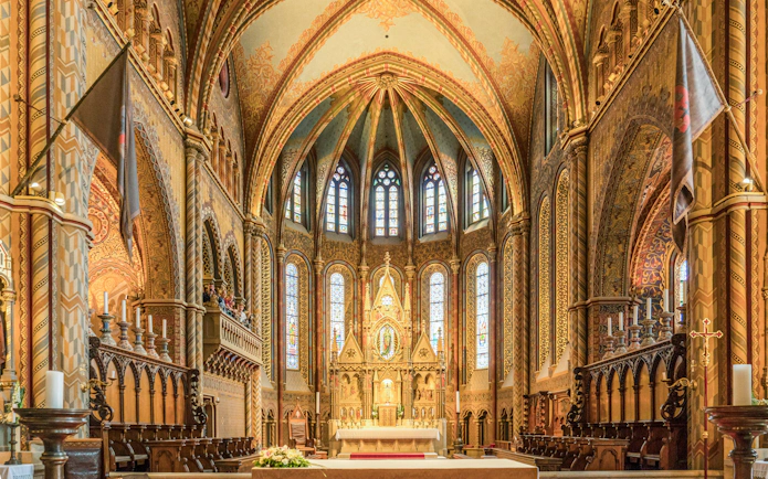Interior of Matthias Church in Budapest with ornate altar and stained glass windows.