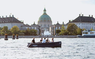 Guests on a boat tour in Copenhagen with Fredrick's Church in the background.