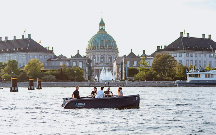 Guests on a boat tour in Copenhagen with Fredrick's Church in the background.