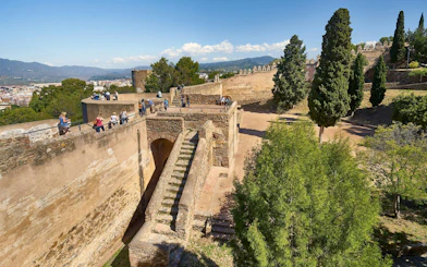 Tourists exploring the historic walls of Gibralfaro Castle in Málaga, Spain.