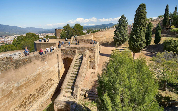 Tourists exploring the historic walls of Gibralfaro Castle in Málaga, Spain.