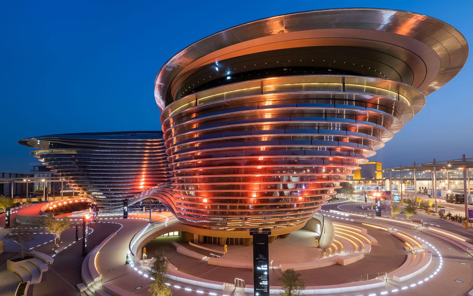 Exterior view of Expo City Dubai's illuminated modern architecture at dusk.