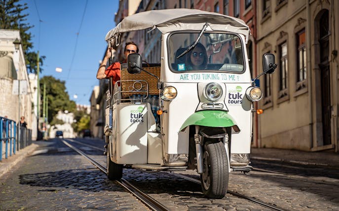 Private electric tuk tuk on cobblestone street during half day sightseeing tour.