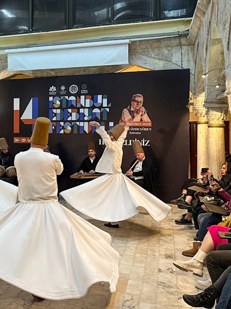 Whirling Dervishes performing at Mevlevi Sema ceremony in Istanbul, with audience watching.