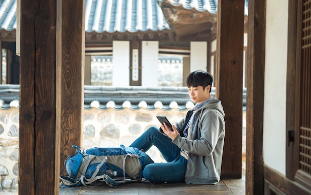 Traveler using tablet with Korea Unlimited Data eSIM at traditional Korean house.
